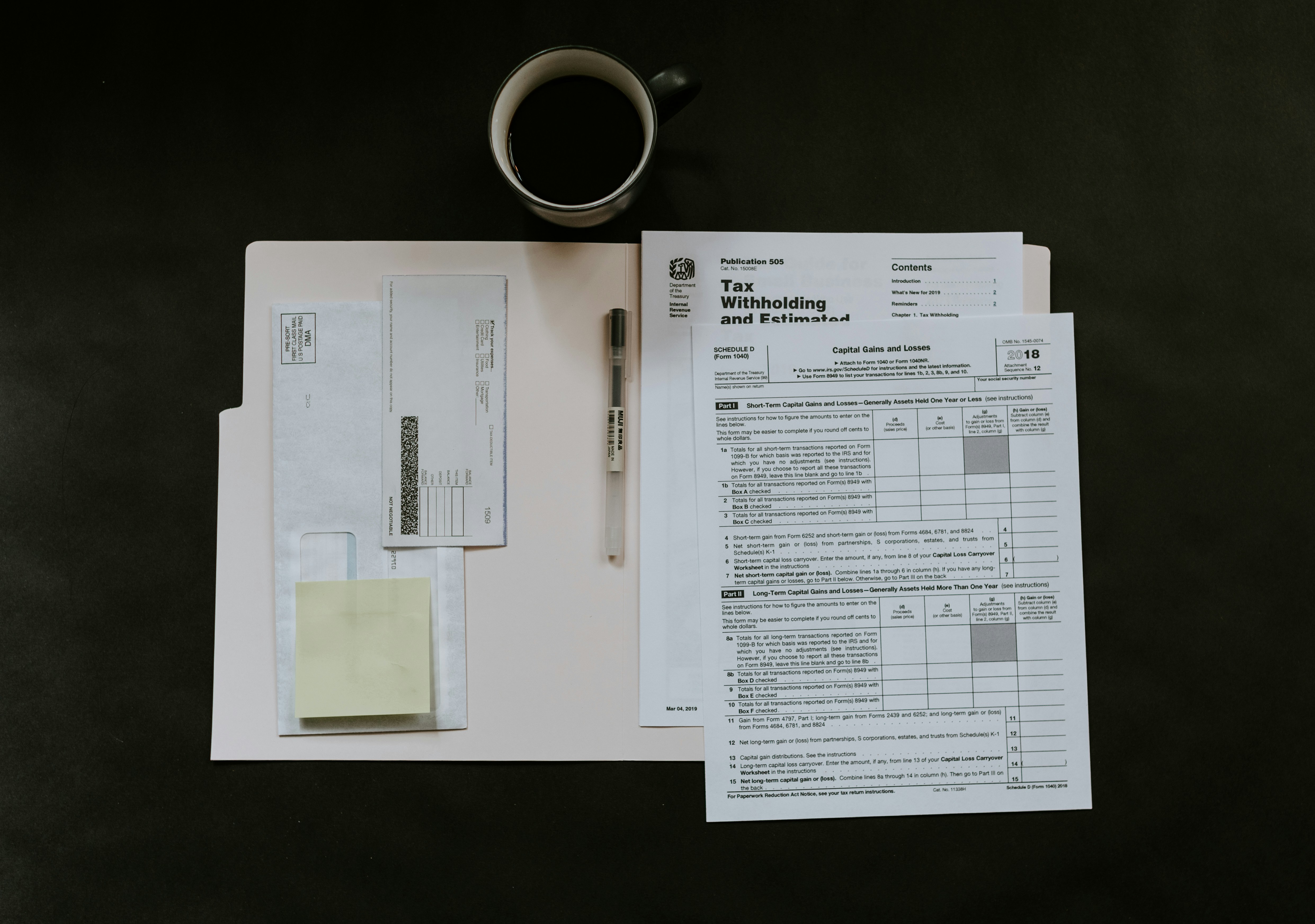 Tax documents sitting inside a folder near a cup of coffee on a desk.